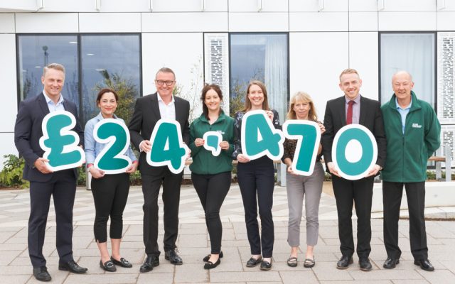 A group of people hold green numbers £24,470