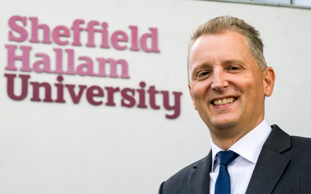 Solicitor Giles Searby Stood In Front of Sheffield Hallam University Sign
